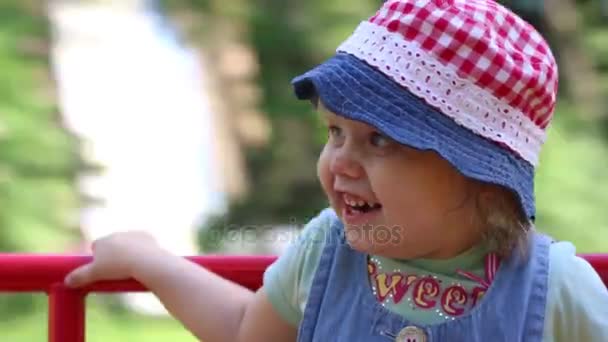 Menina bonito feliz se divertindo no carrossel no parque de verão — Vídeo de Stock