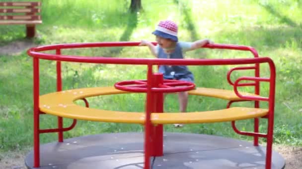 Fröhliches Mädchen hat Spaß auf Karussell im sommergrünen Park — Stockvideo