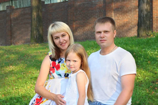 Madre embarazada, padre, hija pequeña posan en el parque de verano — Foto de Stock