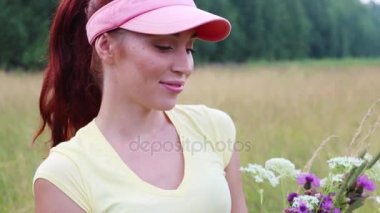 Güzel kız şapkalı kır çiçekleri yaz akşamları kokluyor.