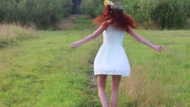 Όμορφη γυναίκα στο στεφάνι περιστροφές στην χλόη κοντά σε δάση στο καλοκαιρινό βράδυ — Αρχείο Βίντεο