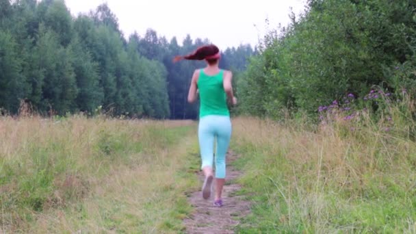 Ragazza corre lì e torna sul sentiero vicino alla foresta la sera d'estate — Video Stock