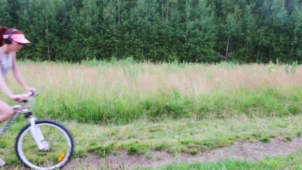 Bella ragazza va in bicicletta in estate foresta verde sul sentiero — Video Stock