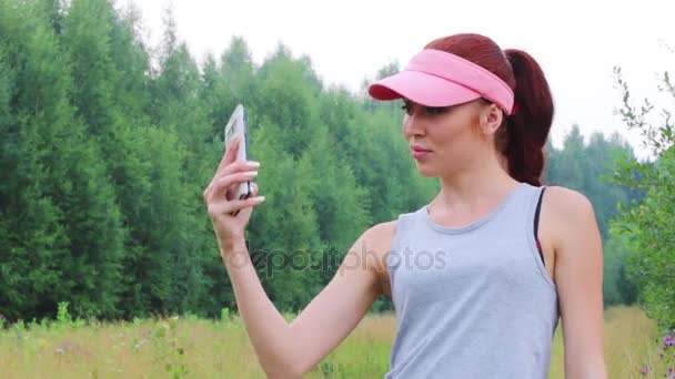 Νεαρή γυναίκα στο καπάκι κάνει selfie στο καλοκαίρι στο δάσος — Αρχείο Βίντεο