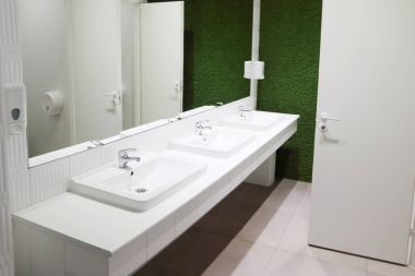 Üç beyaz lavabolar tuvalet büyük ayna ve yeşil çim duvar