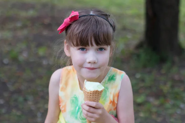 Красивая маленькая девочка в цветном сарафане ест мороженое — стоковое фото