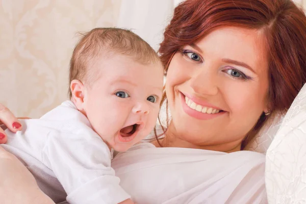 Young mother was lying on the bed, holding the hands of his chil — Stock Photo, Image