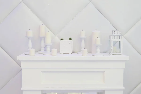 Lareira decorativa branca, velas, relógio, lanterna, paredes brancas — Fotografia de Stock
