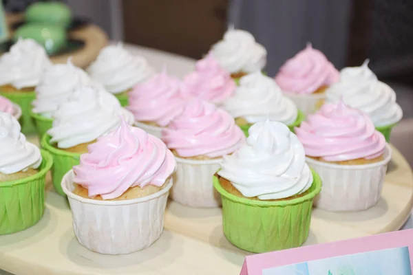 Zoete witte en roze cupcakes zijn op tafel tijdens viering — Stockfoto
