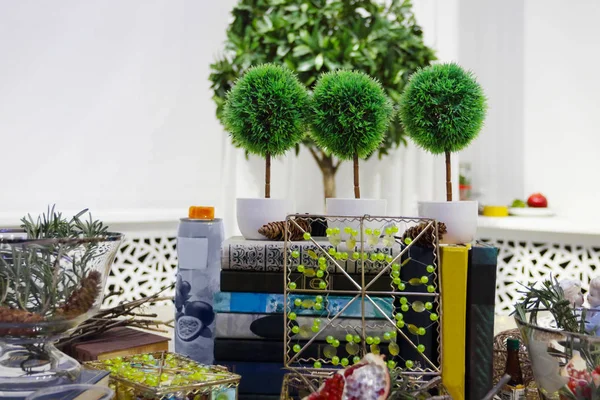 Trois petits arbres artificiels, d'autres décorations et livres — Photo