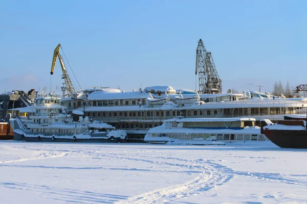 White beautiful passenger ship in frozen river and cranes in win — Stock Photo, Image