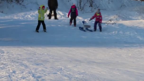 Meisje skiër dia's naar beneden vanaf de heuvel op zonnige winterdag, drie onherkenbaar mensen zijn op heuvel — Stockvideo