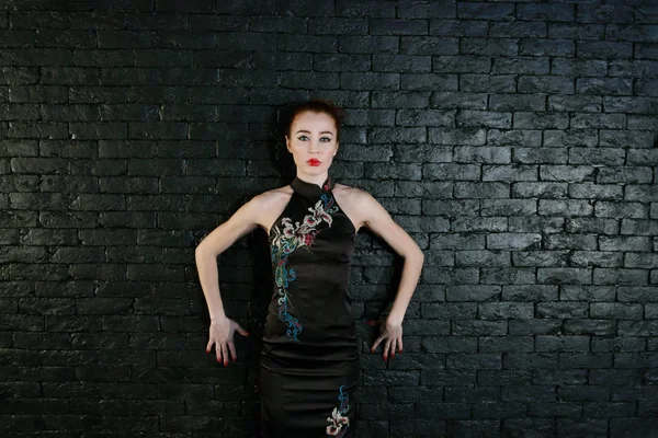 Young woman in black dress with makeup poses in studio — Stock Photo, Image