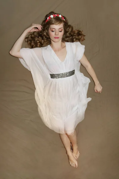 침대에 장미 화 환과 흰색 드레스에 아름 다운 여자 — 스톡 사진