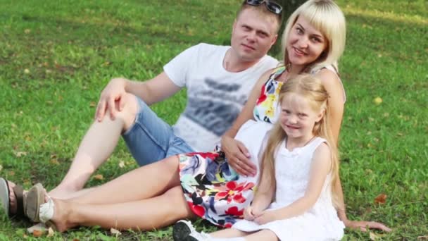 Schwangere Mutter, Vater, kleine Tochter winken auf Gras im Sommerpark — Stockvideo