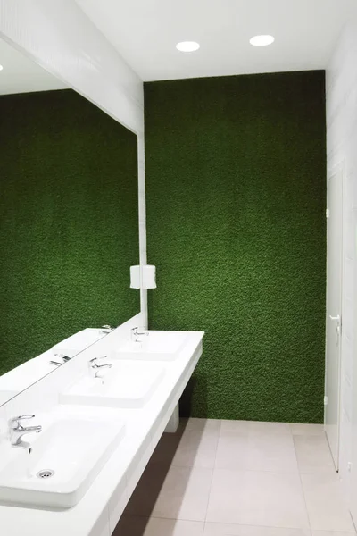 Trzy białe umywalki w pusty WC duże lustro i zielony trawnik — Zdjęcie stockowe