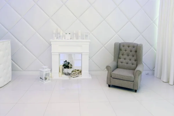 Habitación blanca con chimenea decorativa, velas, sillón — Foto de Stock