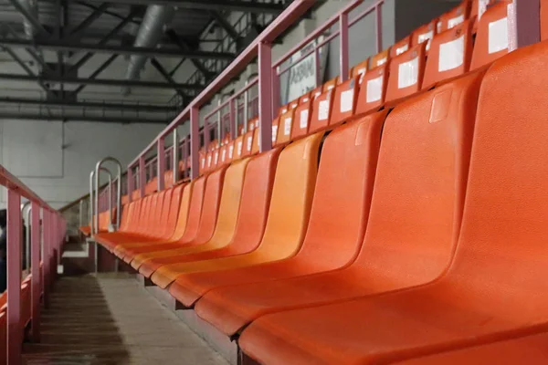 Filas de asientos de plástico naranja en el moderno estadio vacío — Foto de Stock