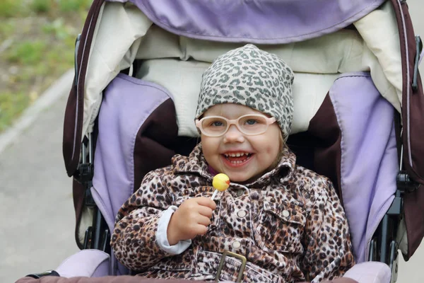 Menina bonito pequeno feliz em óculos falsos mantém pirulito e sorrisos — Fotografia de Stock