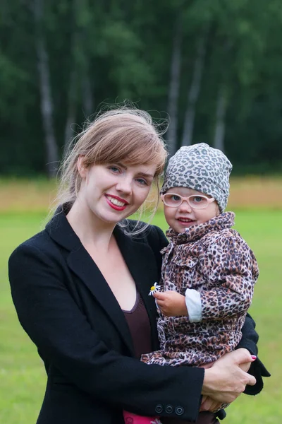 Young smiling woman holds little cute daughter outdoor at summer — Stock Photo, Image