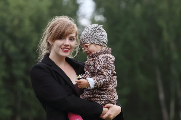 Junge hübsche Frau hält kleine Tochter an Sommertag im Freien — Stockfoto