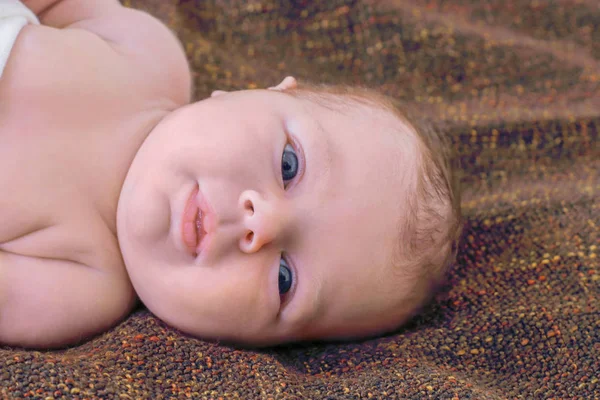 Il bambino è avvolto in un panno bianco, tranquillamente sdraiato sul letto un — Foto Stock