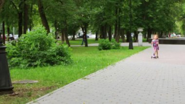 Kızıl saçlı sevimli küçük kız scooter yeşil yaz park gezintisi