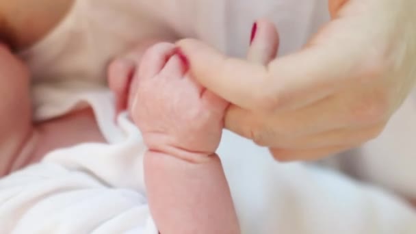 Pequeno bebê chupa seu peito mãe e mão mãe toca pequenos dedos na cama, foco em dedos — Vídeo de Stock