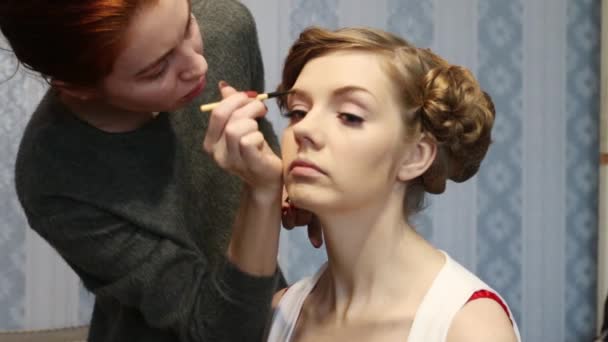 Truccatore fa trucco per la donna con acconciatura in camera — Video Stock