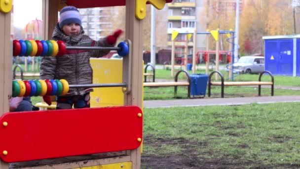 Küçük mutlu çocuk sıcak giysiler içinde renkli halkalar ile sahada oynuyor. — Stok video