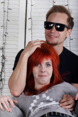 Komik Kızıl saçlı kız ve genç adam beyaz stu duvarının yakınında kucaklamak