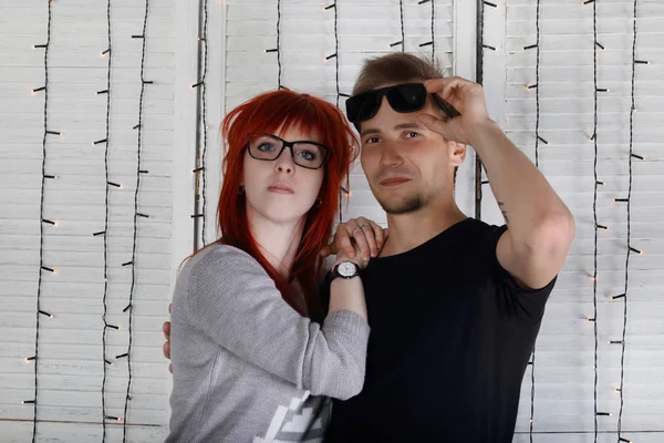 Hübsches Mädchen mit Brille und junger Mann posieren zusammen in der Nähe von Wand in — Stockfoto