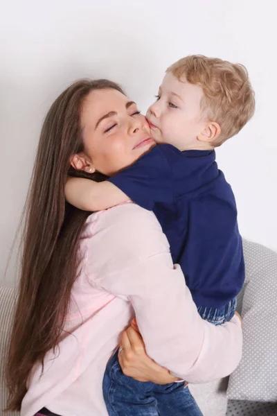 Young mother with long hair embraces her little blonde cute son — Stock Photo, Image