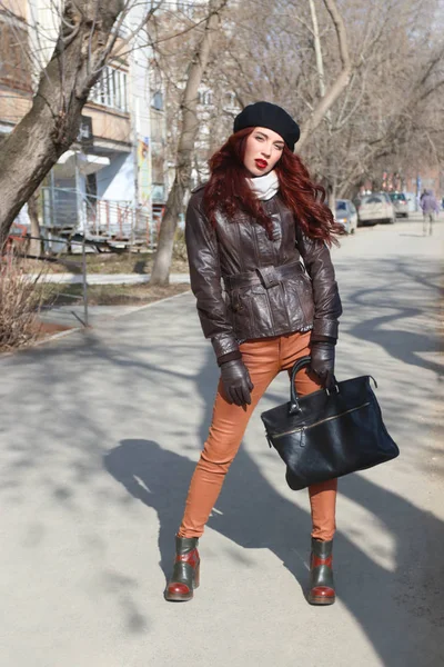 Dívka v kožené bundě a rukavice stojí na ulici na slunné spri — Stock fotografie