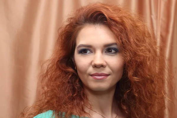 Mulher bonita com cabelo vermelho e maquiagem posa perto de curtai — Fotografia de Stock