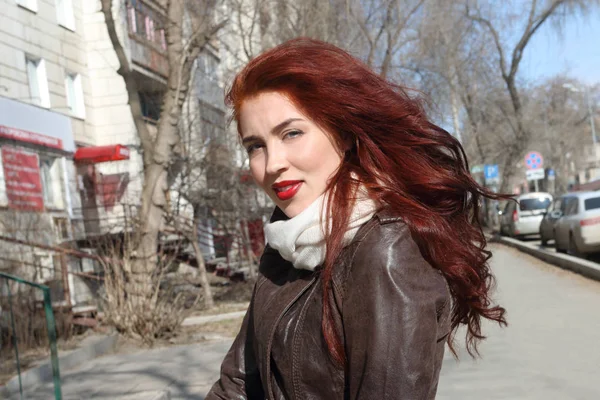 Pretty woman with long hair in leather jacket stands outdoor at — Stock Photo, Image