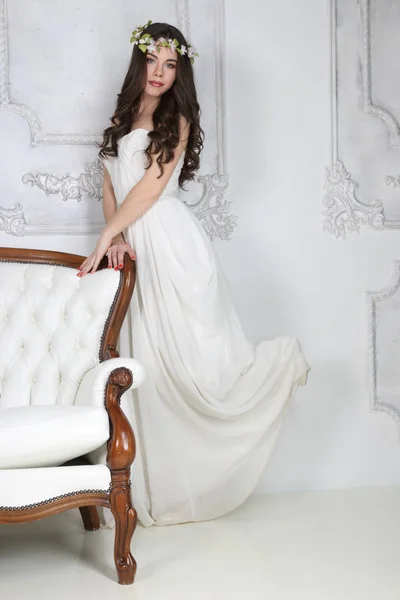 若いかわいいブルネットの花輪、ソファの近くの長いドレス ポーズ — ストック写真