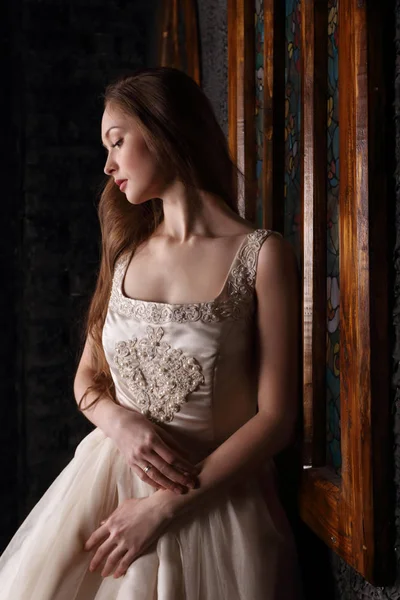 Красивая молодая женщина в длинном платье стоит у окна в черном Стю — стоковое фото