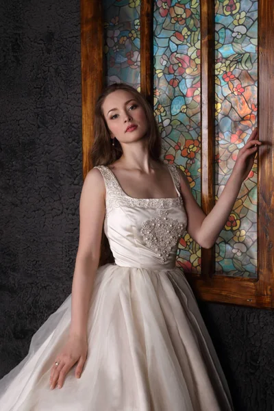 Uzun elbiseli güzel kadın siyah studio penceresinde yakınındaki poz veriyor