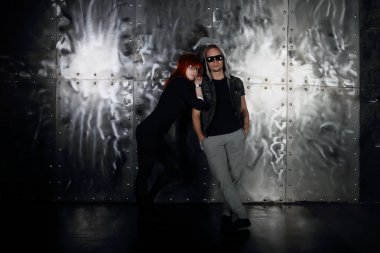 Birlikte poz metal duvar genç kadın ve erkek güneş gözlüğü 