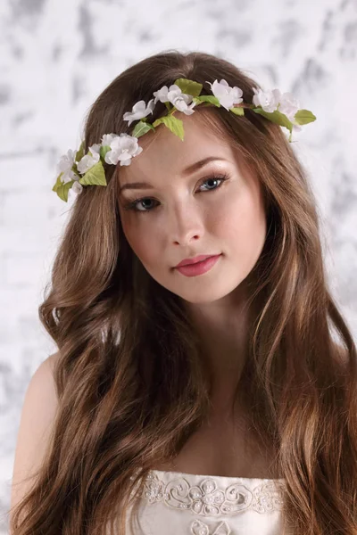 Güzel genç kadın uzun saçlı çelenk içinde beyaz studi teşkil etmektedir.