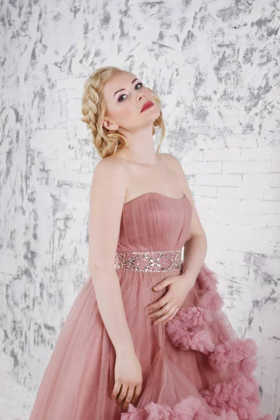 Блондинка в платье с прической позирует у белой стены в s — стоковое фото