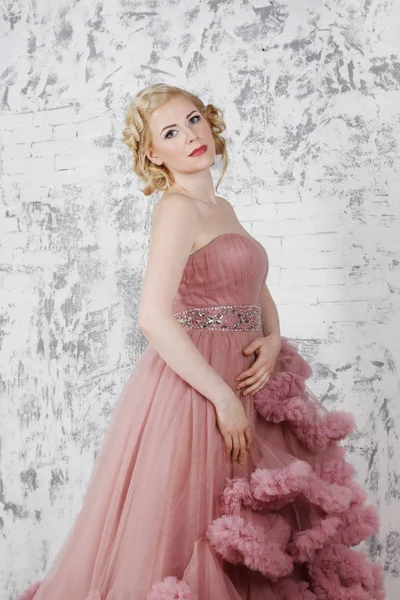 Beyaz duvar s yakınındaki güzel sarışın saç modeli ile elbiseli pozlar