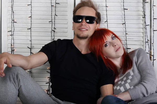 Glücklich rote Haare Mädchen und Mann mit Sonnenbrille sitzt im weißen Studio w — Stockfoto