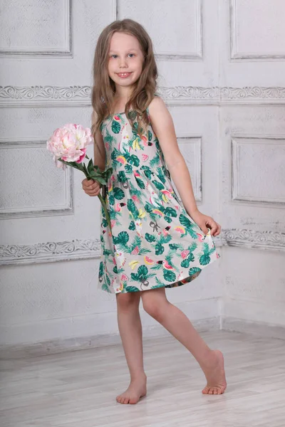 Happy girl in dress with pink big peony poses in white room at h — Stock Photo, Image