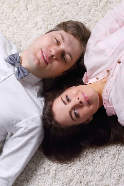 Happy woman and young handsome man in bow tie lie on carpet, top — Stock Photo, Image