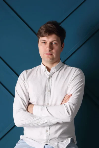 Jovem sério bonito homem de camisa branca posa em estúdio azul — Fotografia de Stock