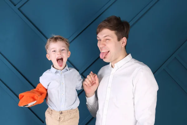 Young handsome father and little son put out tongues in blue stu — Stock Photo, Image