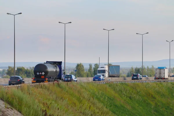 Cars and trucks move on modern highway with lanterns at summer d — Stock Fotó