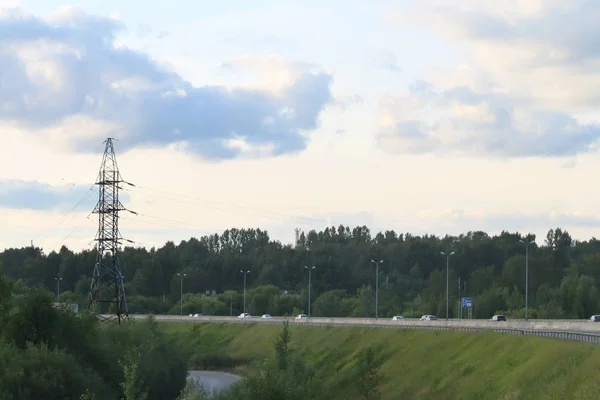 Coches se mueven en la carretera moderna cerca de la línea de transmisión de energía en suma — Foto de Stock